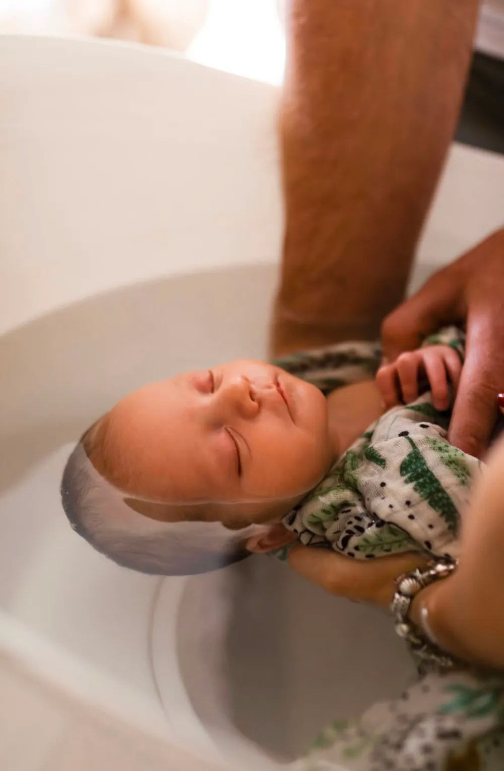 Bain enveloppé accompagné par les deux parents autour de la baignoire