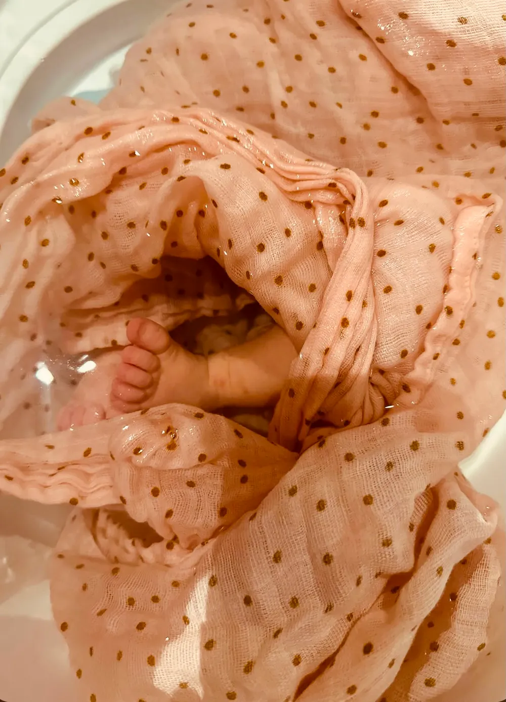 Bébé enveloppé dans un lange rose à pois pendant son bain enveloppé