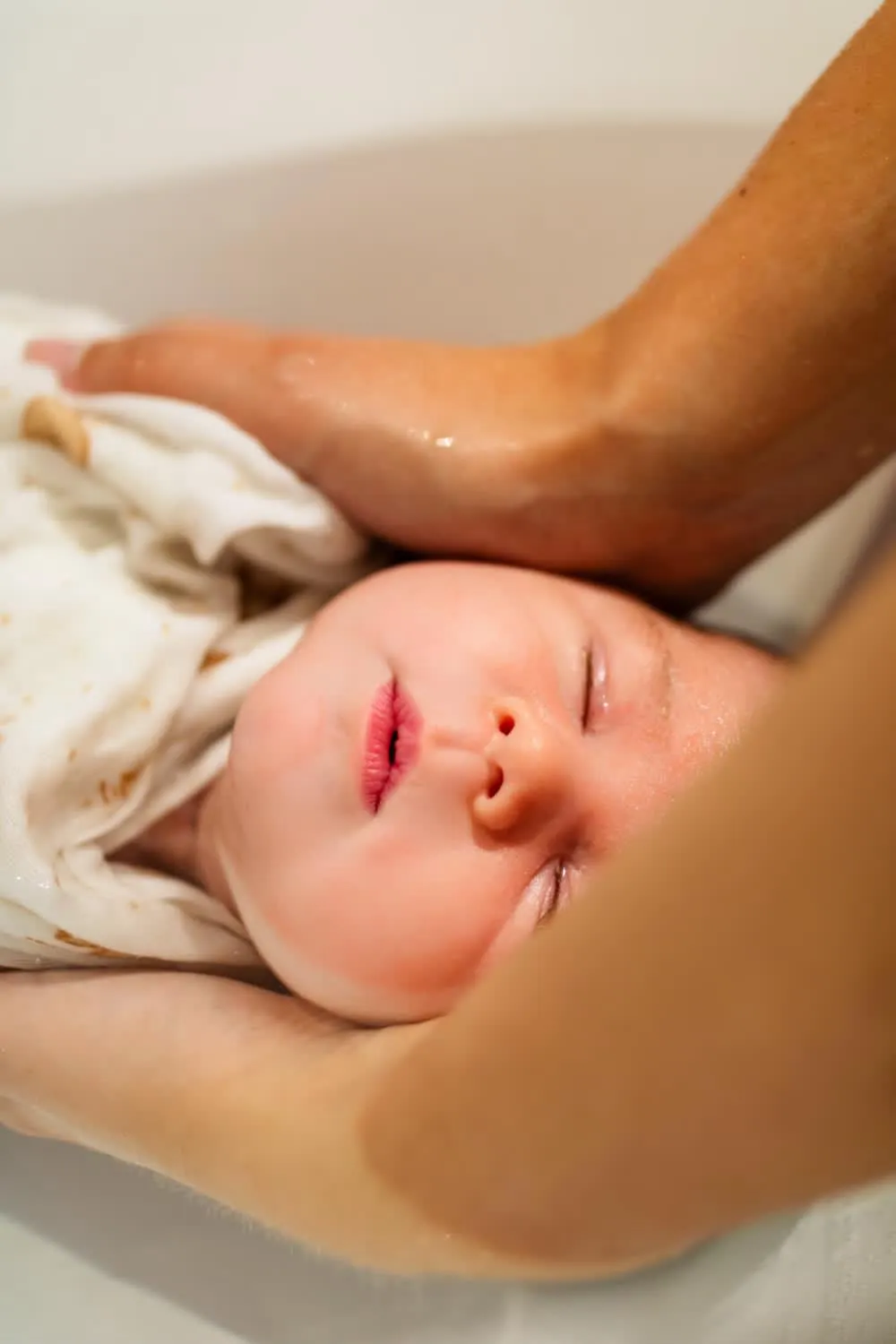 Visage apaisé d'un nouveau-né pendant son bain enveloppé chez BabyMum Relax