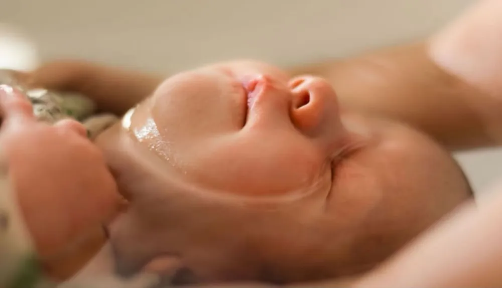Gros plan sur le visage détendu du bébé pendant son bain enveloppé