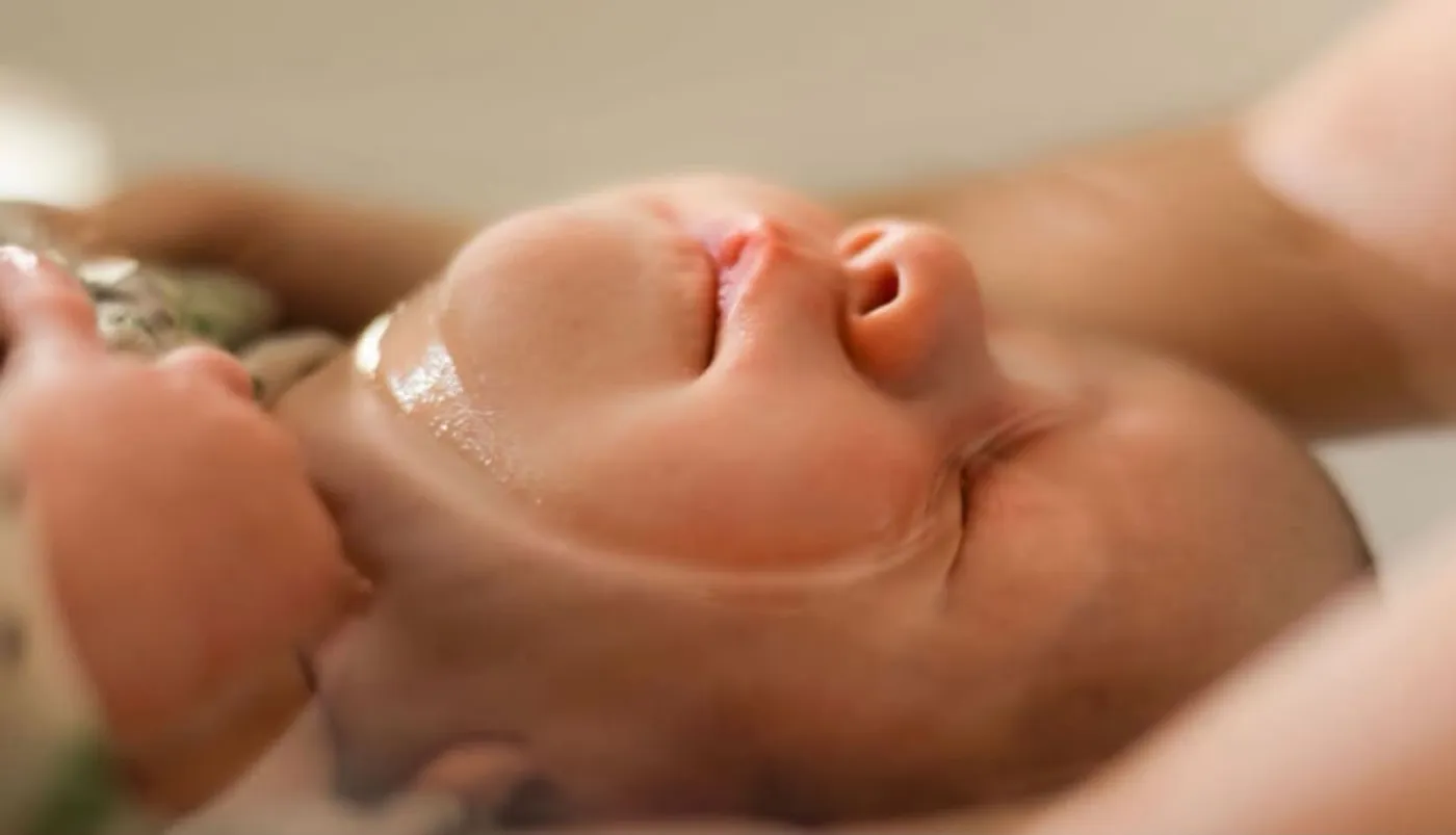 Gros plan sur le visage détendu du bébé pendant son bain enveloppé