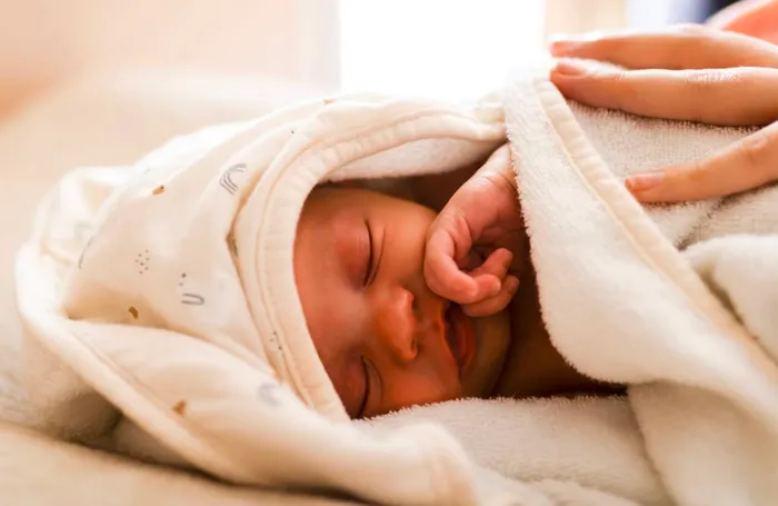 Bébé endormi dans sa cape de bain juste après le soin