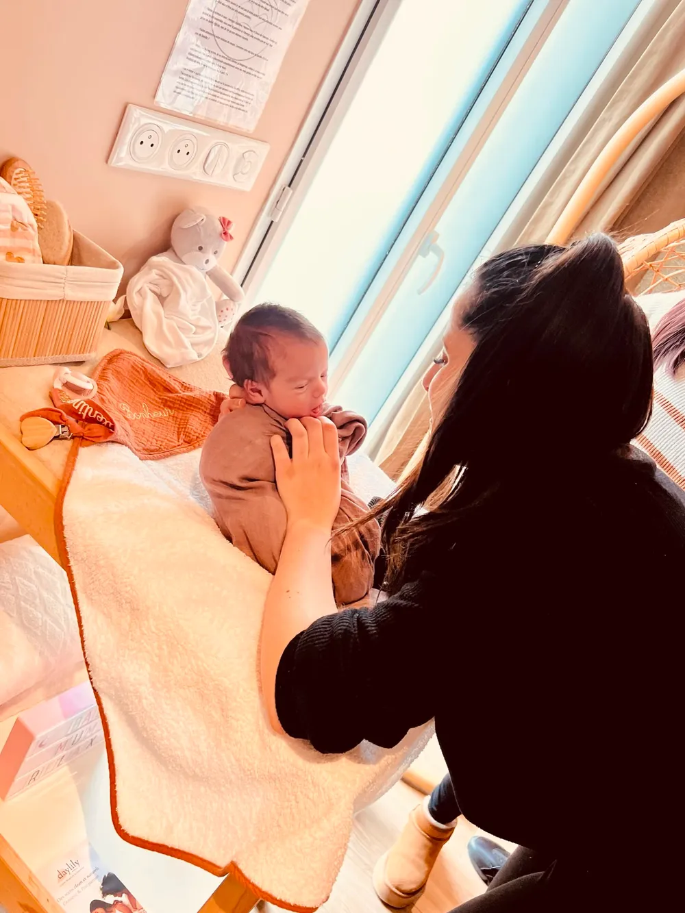 Praticienne installant un bébé emmailloté sur la table de soin