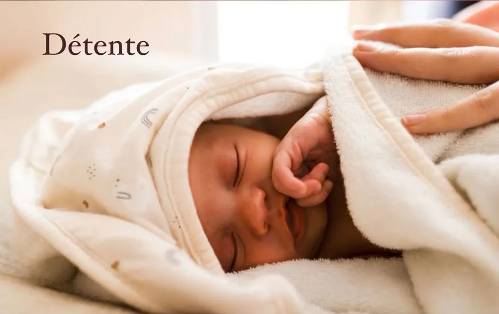 Bébé emmailloté dans une serviette moelleuse, parfaitement détendu après son soin