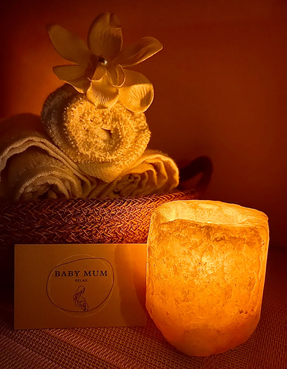 Ambiance chaleureuse de l'institut BabyMum Relax : bougie allumée et serviettes roulées