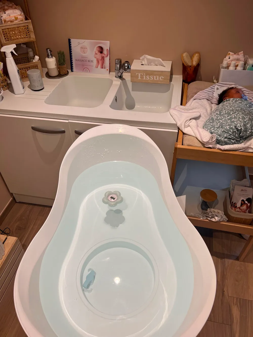 Espace bain enveloppé : baignoire préparée avec thermomètre et table à langer