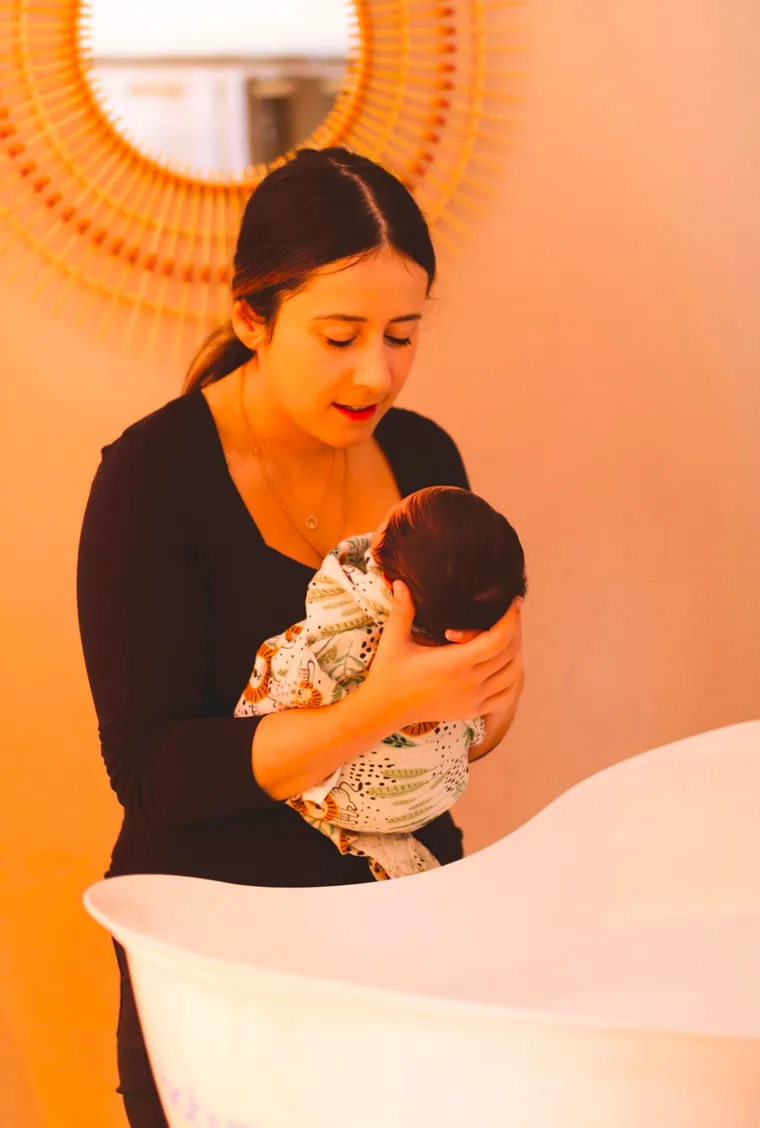 Marilyne portant un bébé emmailloté dans l'espace bain de l'institut